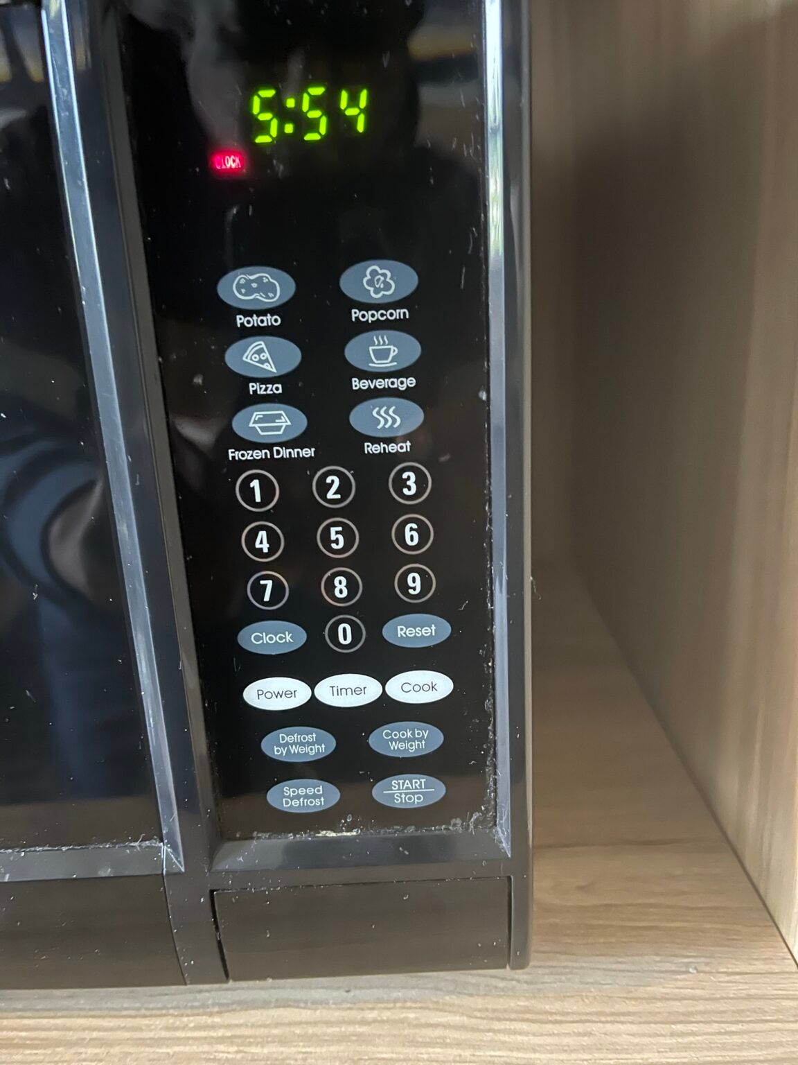 A close up of a microwave displaying the time as 5:54
