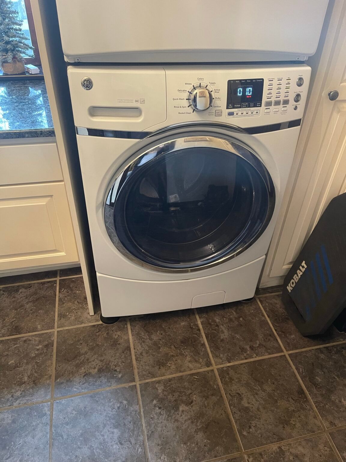 A white washer and dryer are stacked on top of each other in a kitchen.