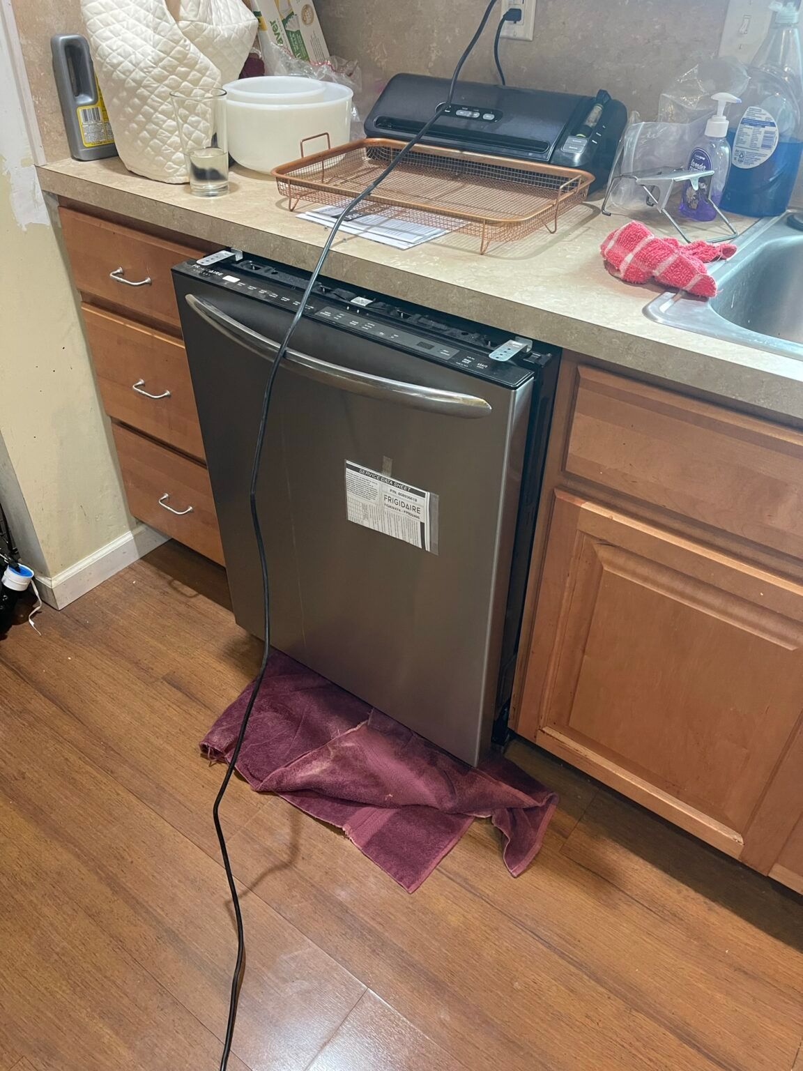 A stainless steel dishwasher is sitting on top of a wooden counter in a kitchen.