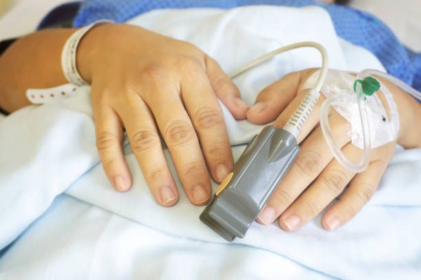 A person is laying in a hospital bed with an iv in their hand.