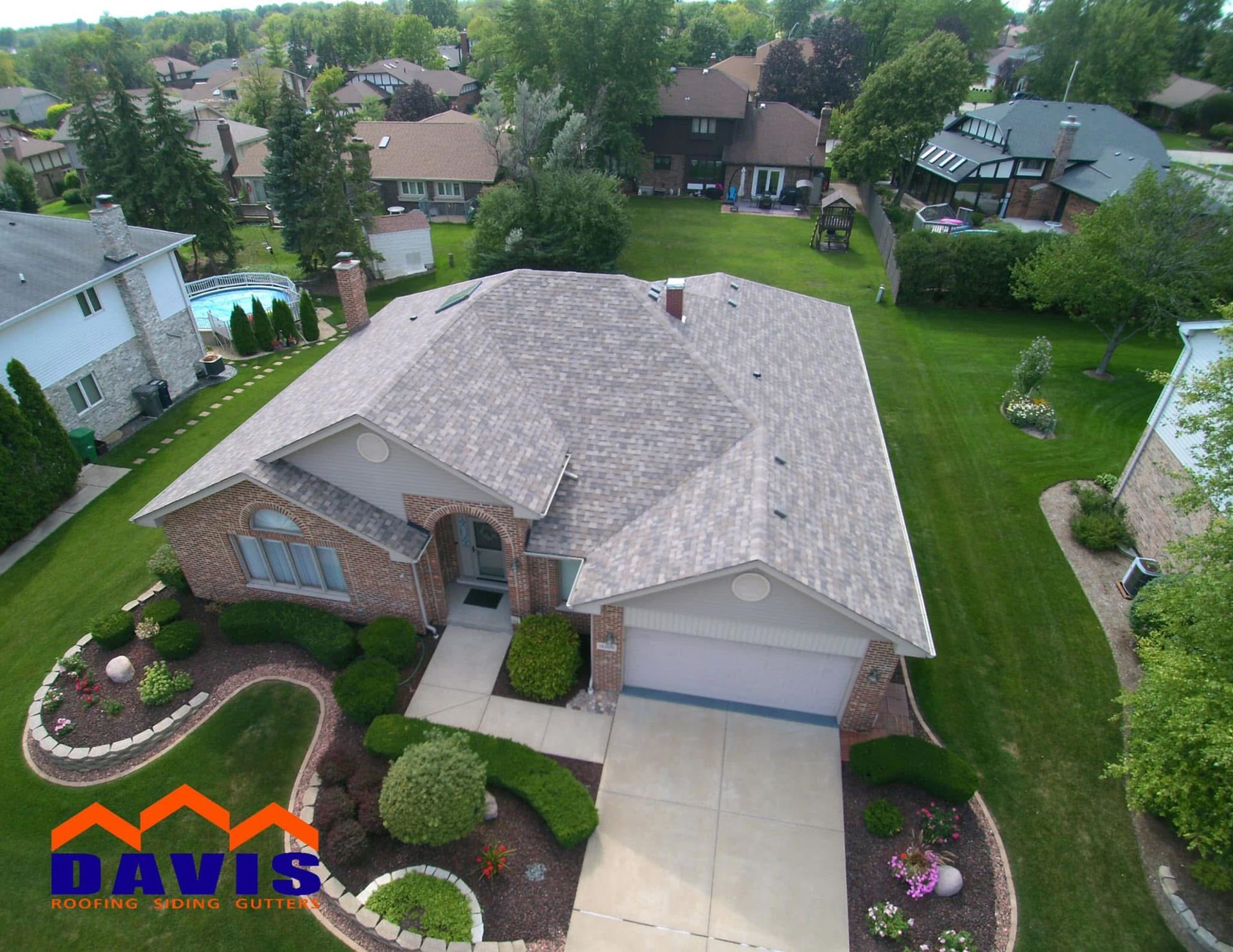 Aerial view of a suburban house with a gray roof and well-manicured lawn.