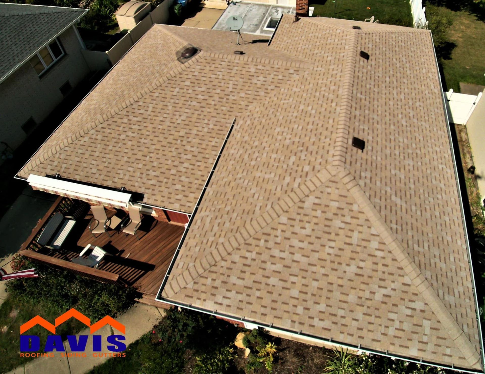 Overhead view of a house with a brown shingle roof, a wooden deck, and surrounding greenery.