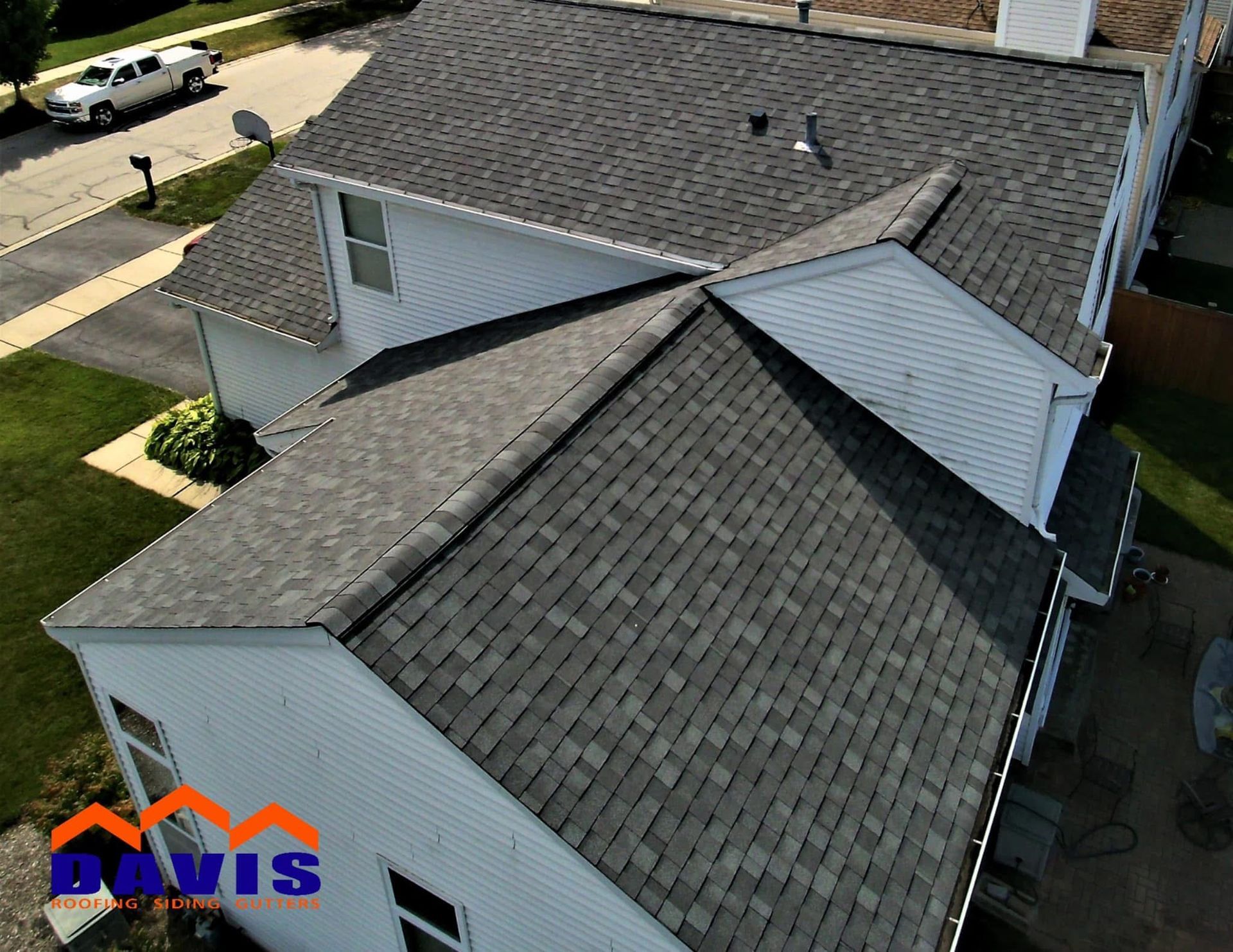 Overhead view of a house with a gray shingle roof, white siding, and green lawn.