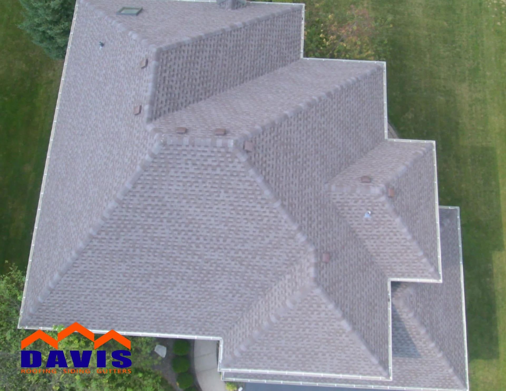 Aerial view of a gray asphalt shingle roof on a house, angled in the frame. The DAVIS logo is in the bottom left corner.