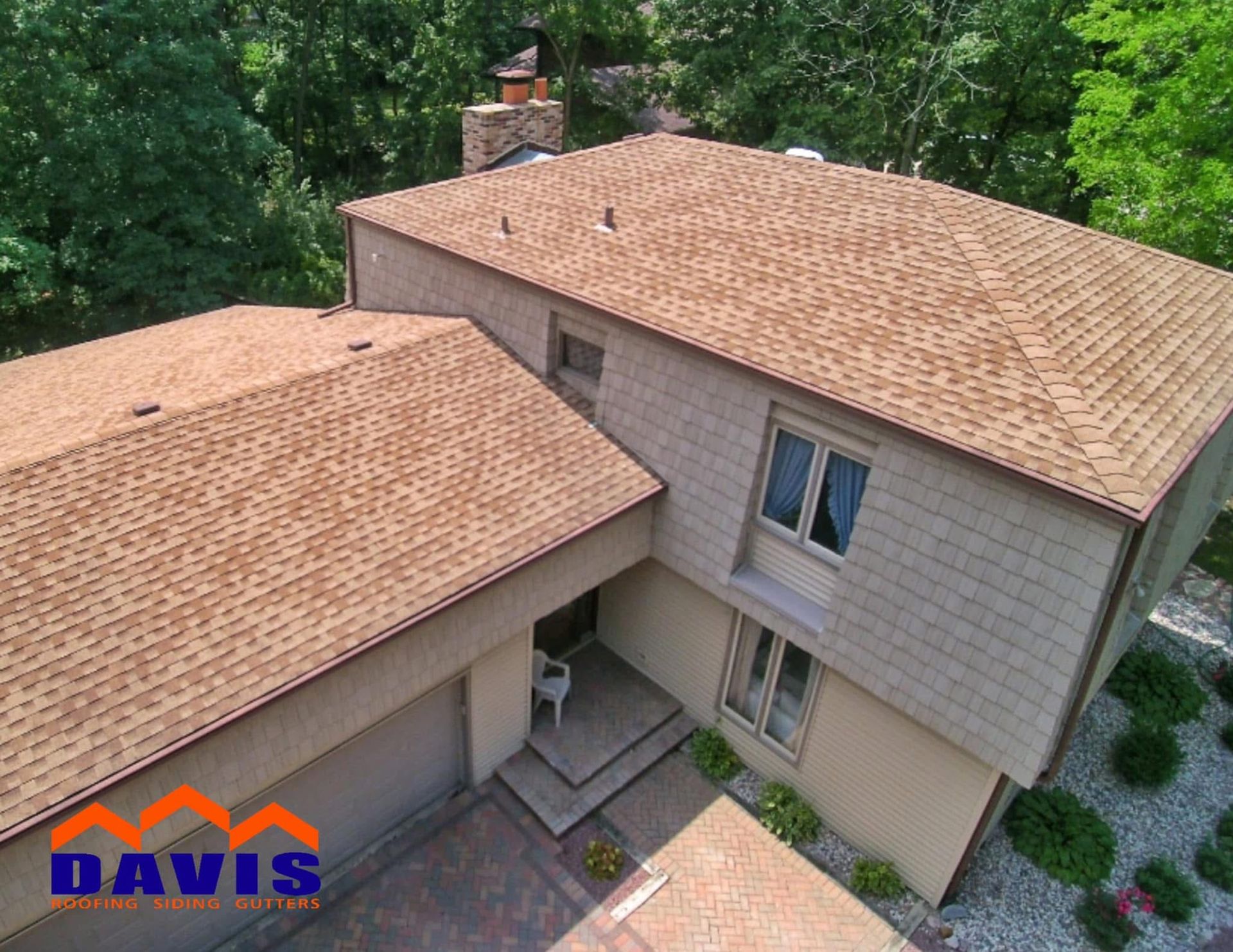 A tan house with a brown shingled roof, trees in the background, Davis logo in the bottom left.