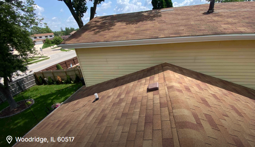 Roof shingles on a house beside a beige siding wall, viewed from above in Woodridge, IL.