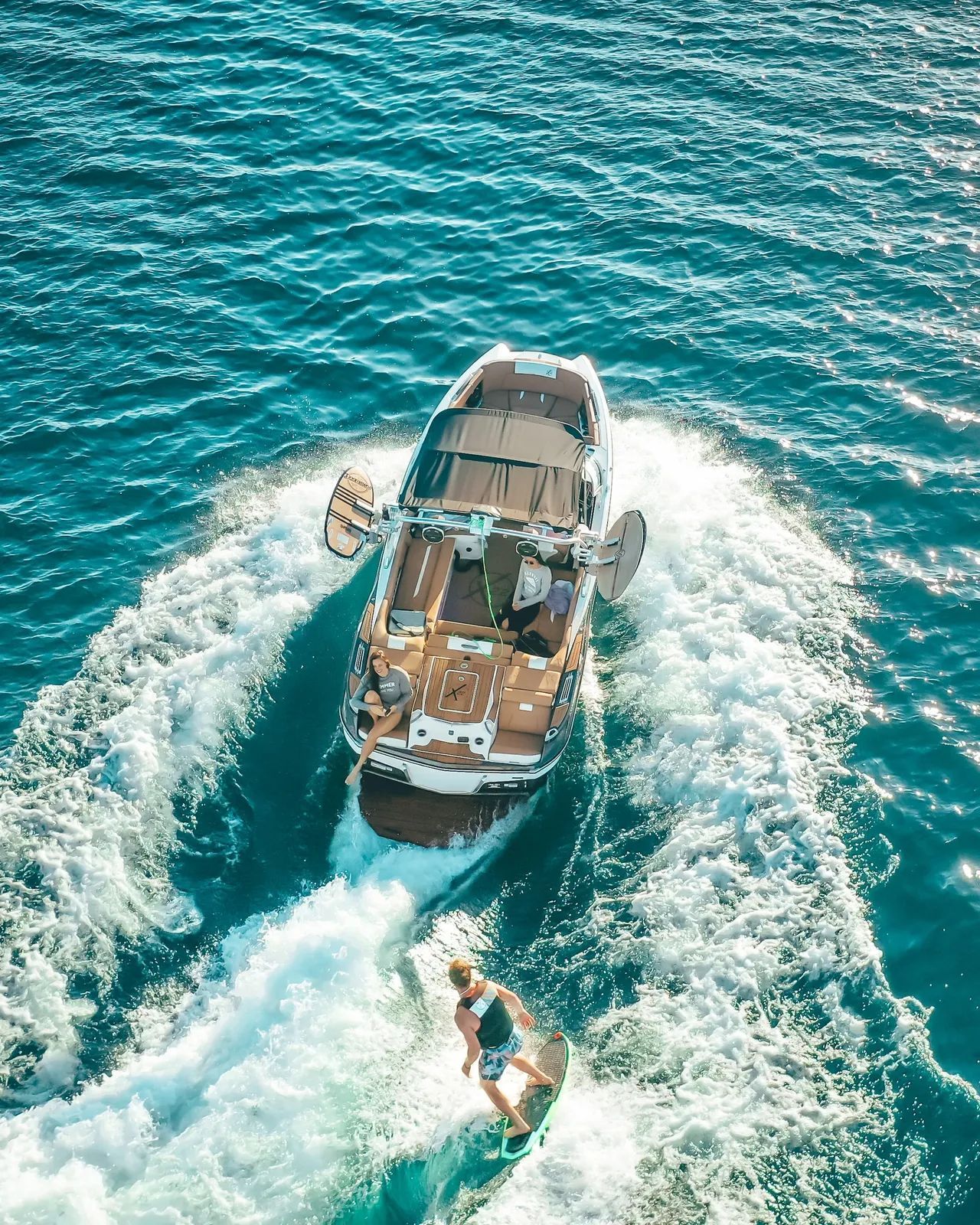 Boat pulling a wakeboarder on blue ocean water.