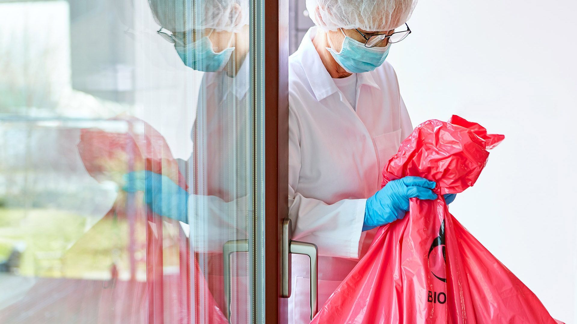 A person carrying a medical waste bag to the disposal area