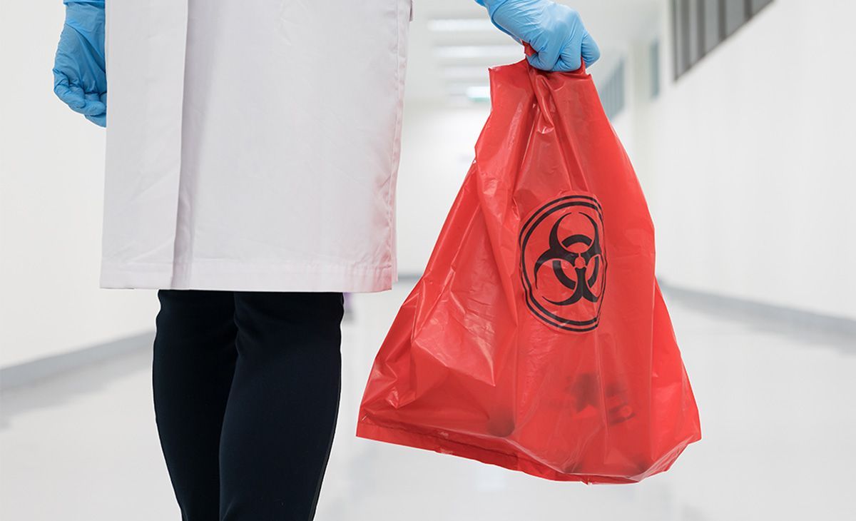 Medical staff holding biohazard waste bag
