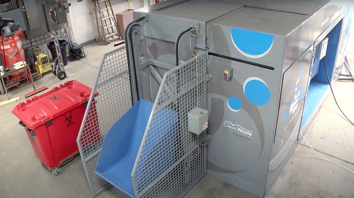 A machine with a lift and a red bin.