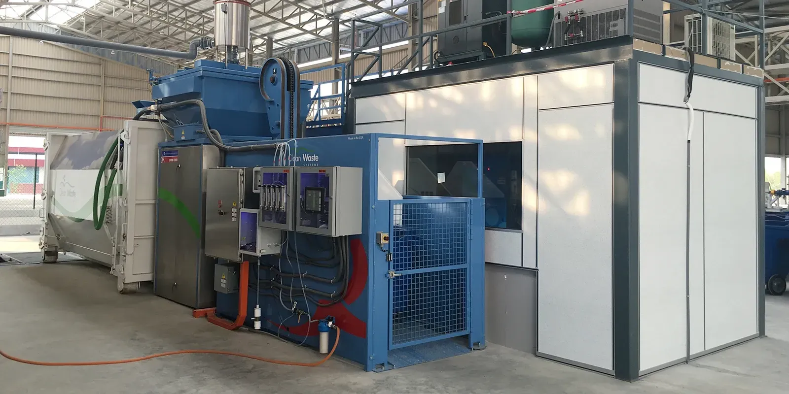 Large industrial machine in a factory setting. Predominantly blue, white, and gray.