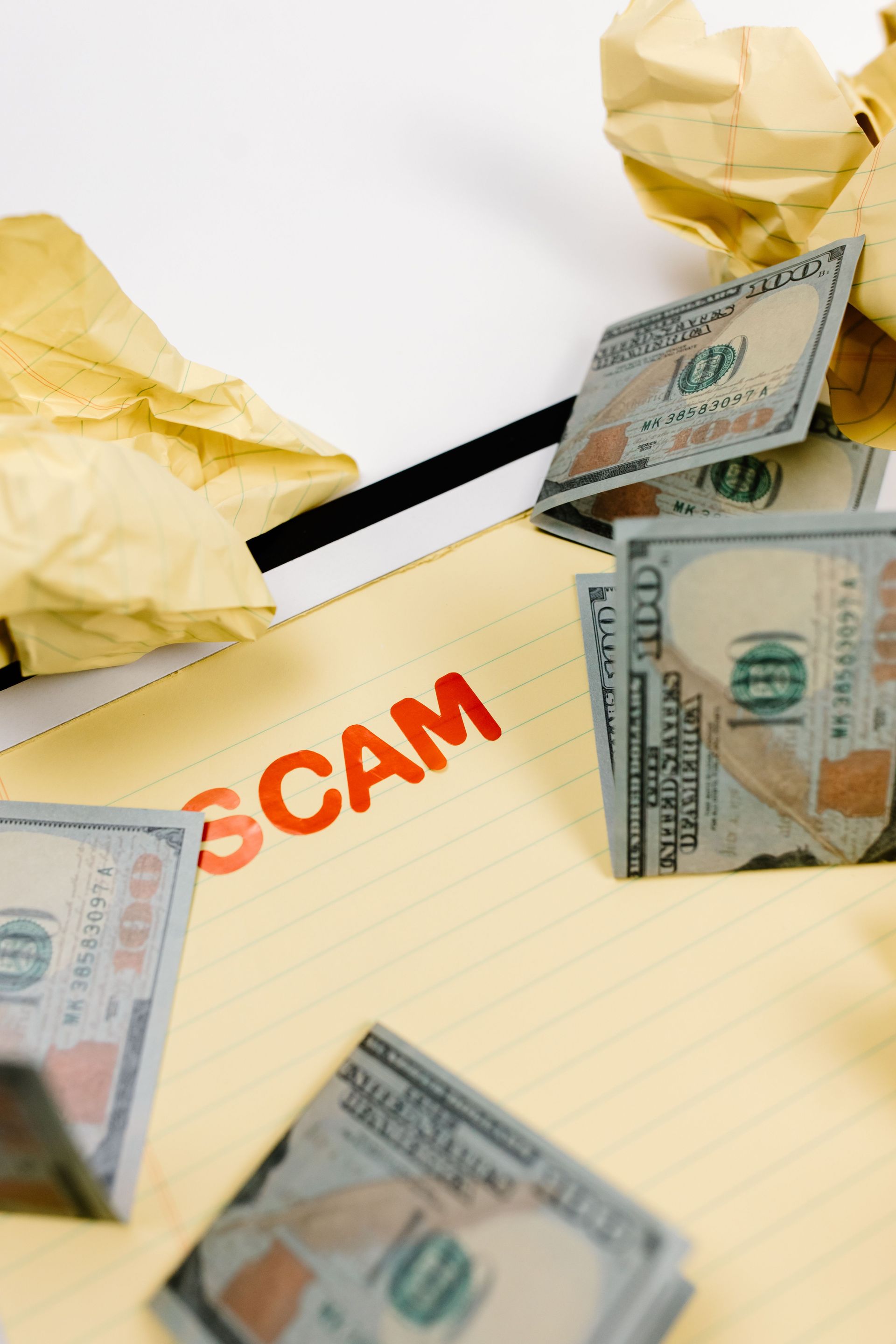 Scam warning with crumpled paper and stacks of dollar bills on a notepad