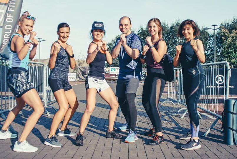 Group of people, fitness enthusiasts, in sportswear, posing in a boxing stance outdoors.