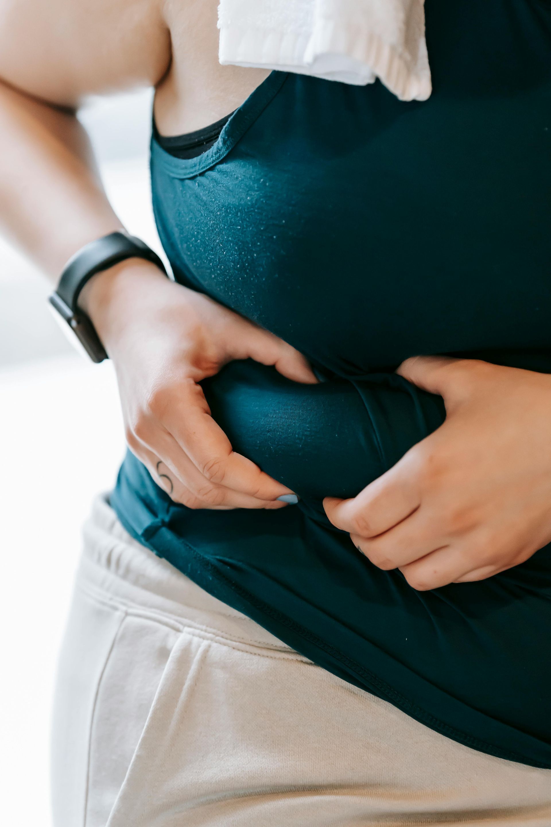 Person in athletic wear pinching belly fat.