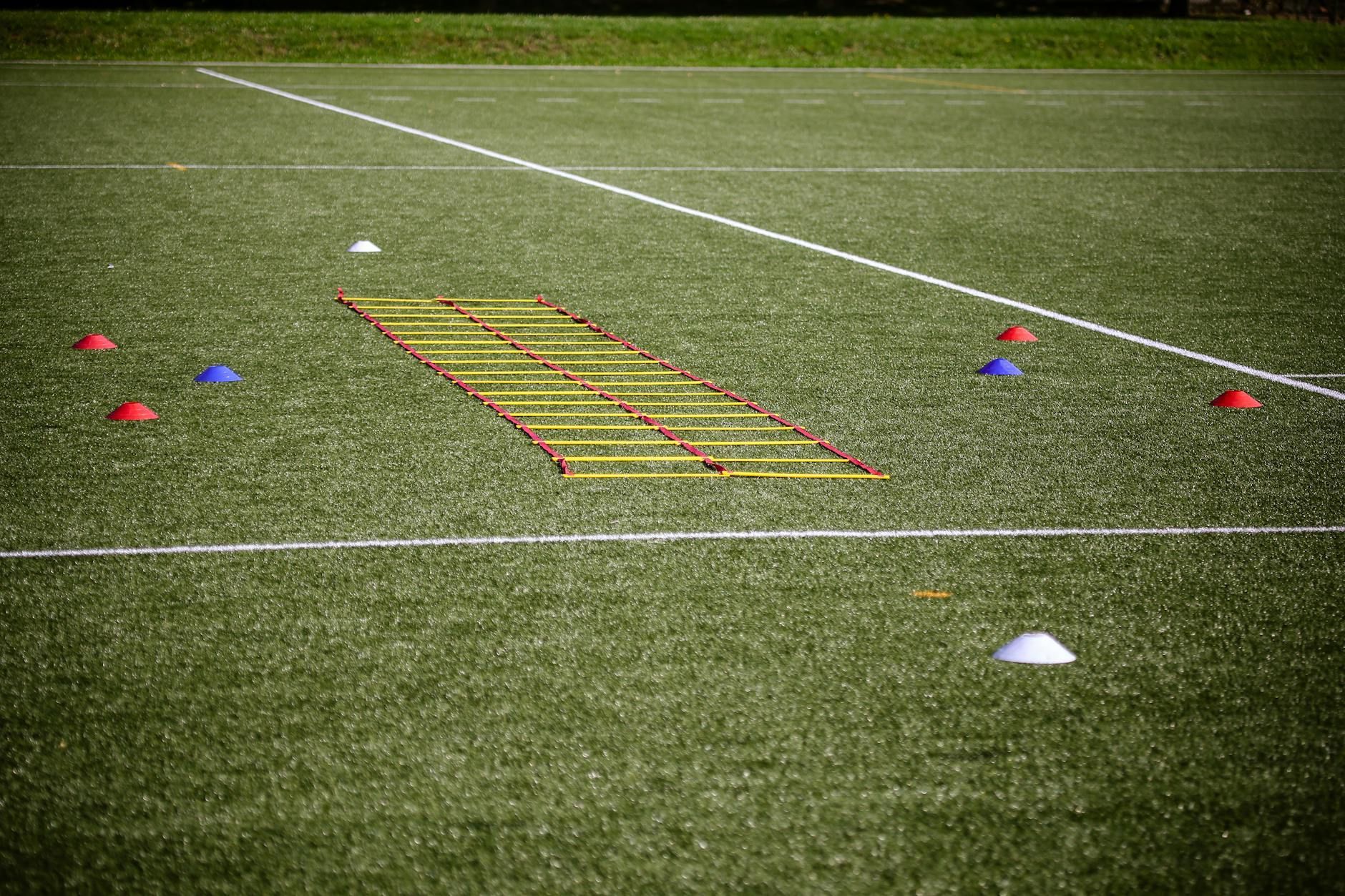 Agility ladder on a soccer field with colorful cones and markers