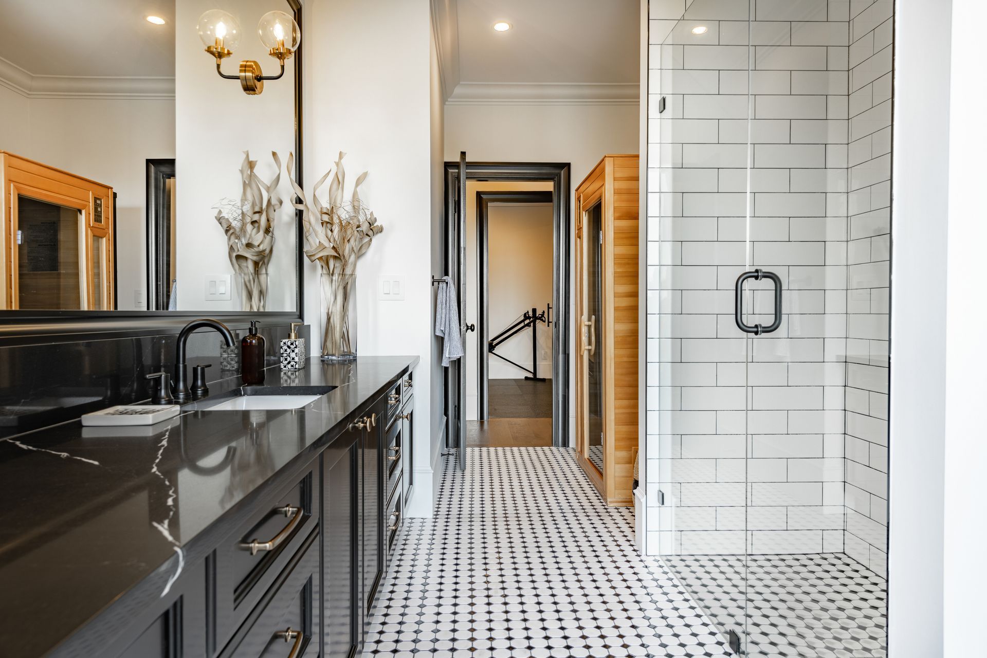 Bathroom with black countertop, white subway tile shower, and patterned floor. A sauna is visible.