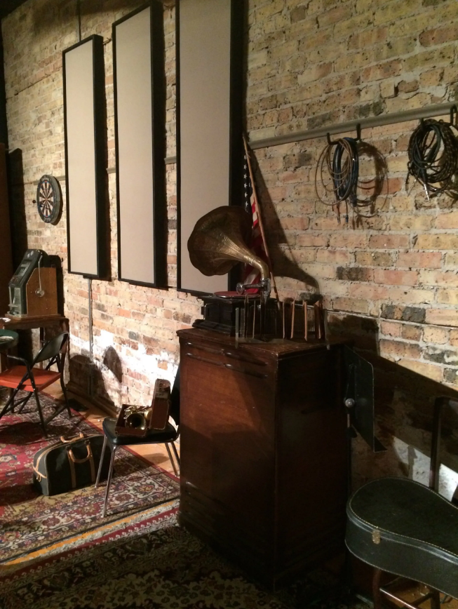 A room with a brick wall and a gramophone on a dresser.