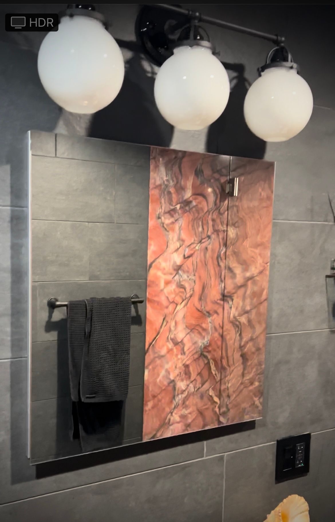 A bathroom mirror with three white globe lights above it