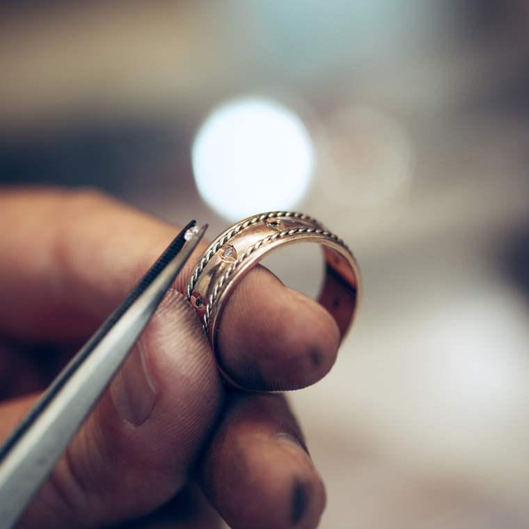 An ornate gold cocktail ring with a central diamond surrounded by clear, pink, green, purple, and yellow gemstones.