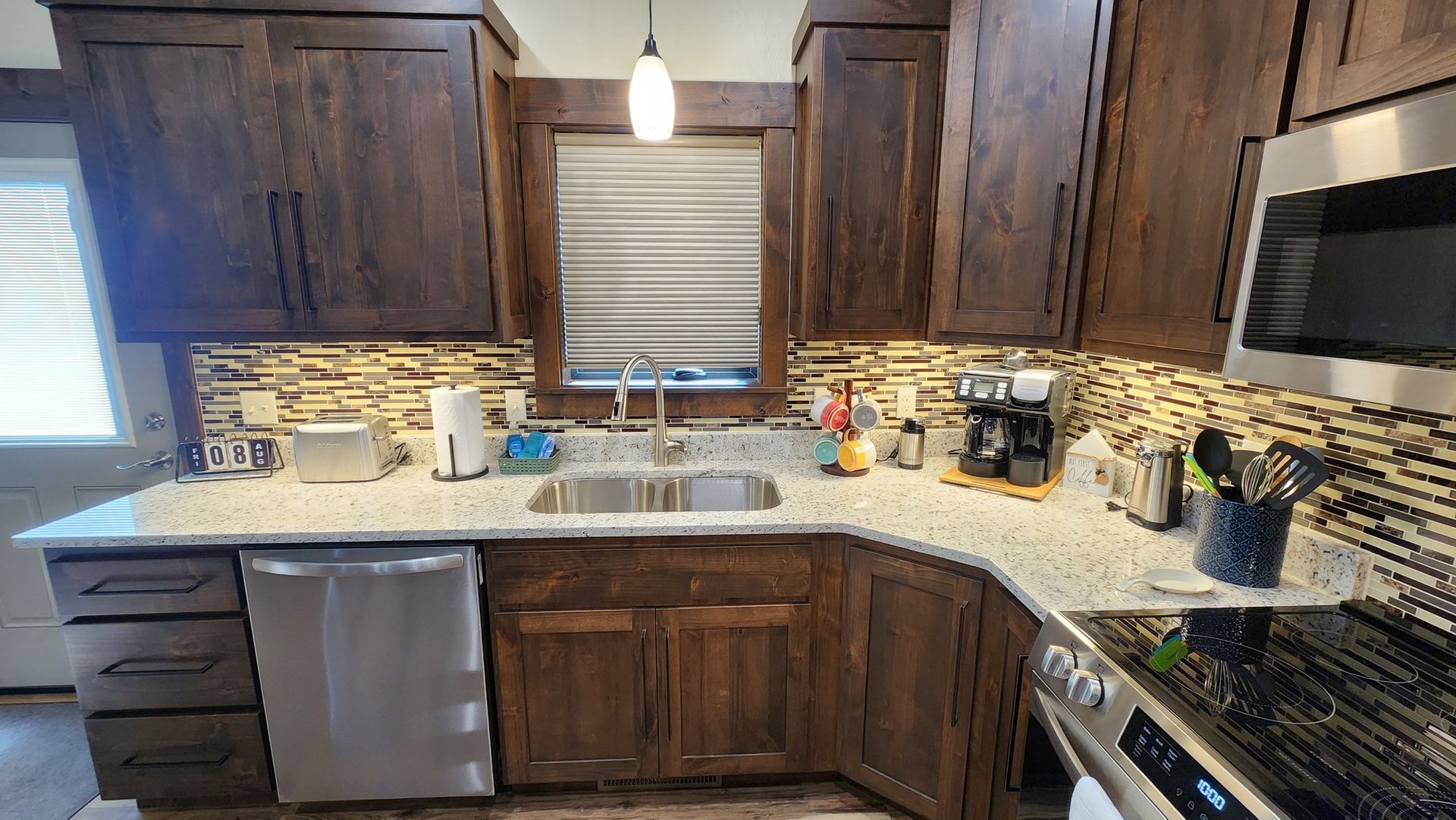 Dark wood kitchen with stainless steel appliances, granite countertops, and tiled backsplash.