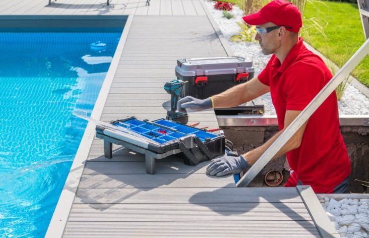 Worker in red uniform fixing poolside decking beside a swimming pool