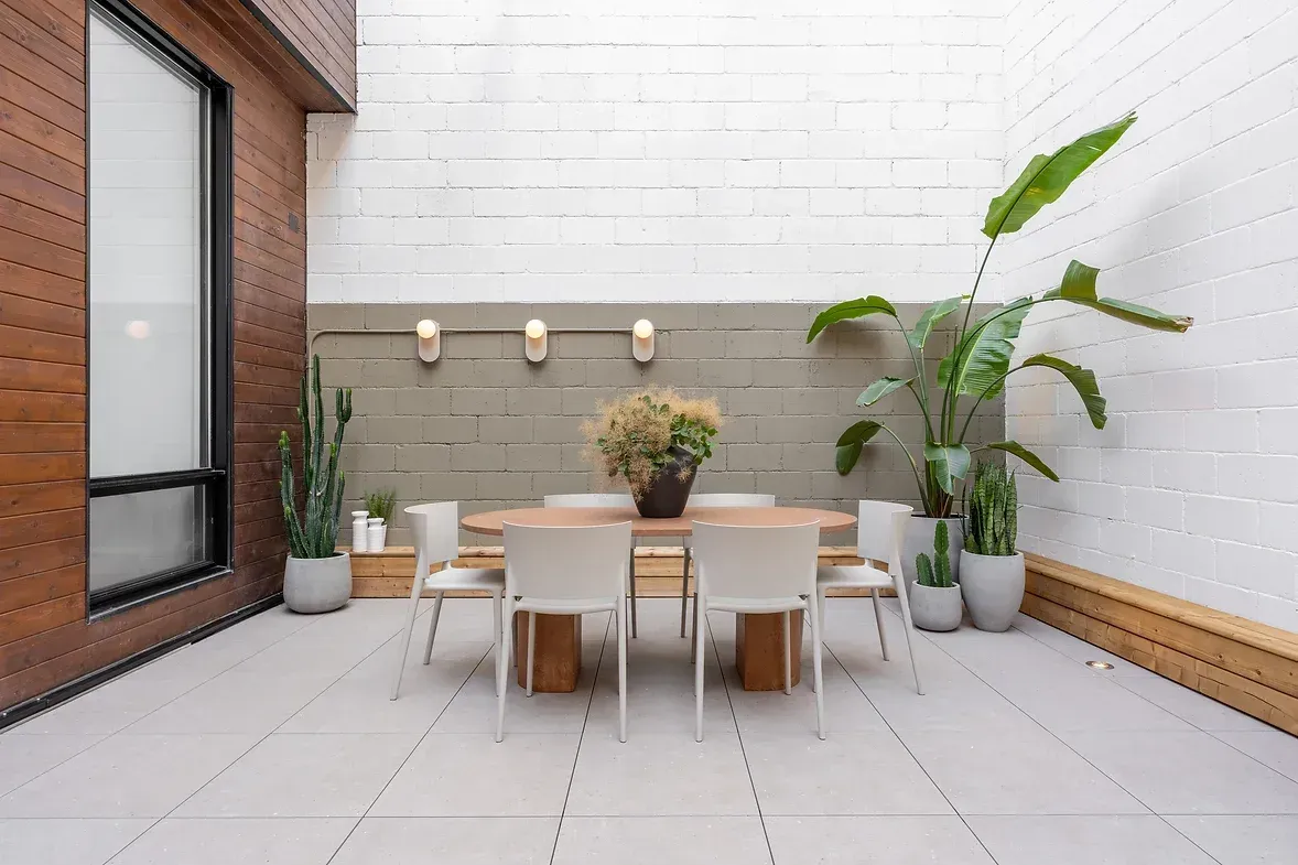 Un patio avec une table, des chaises et des plantes en pot.