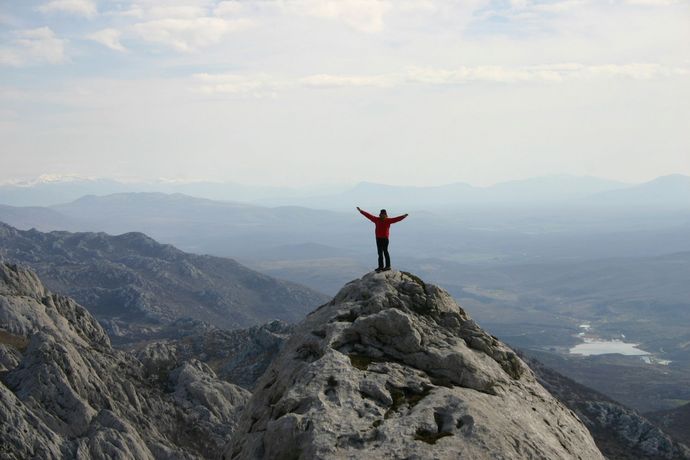 A person standing on top of a mountain with their arms outstretched