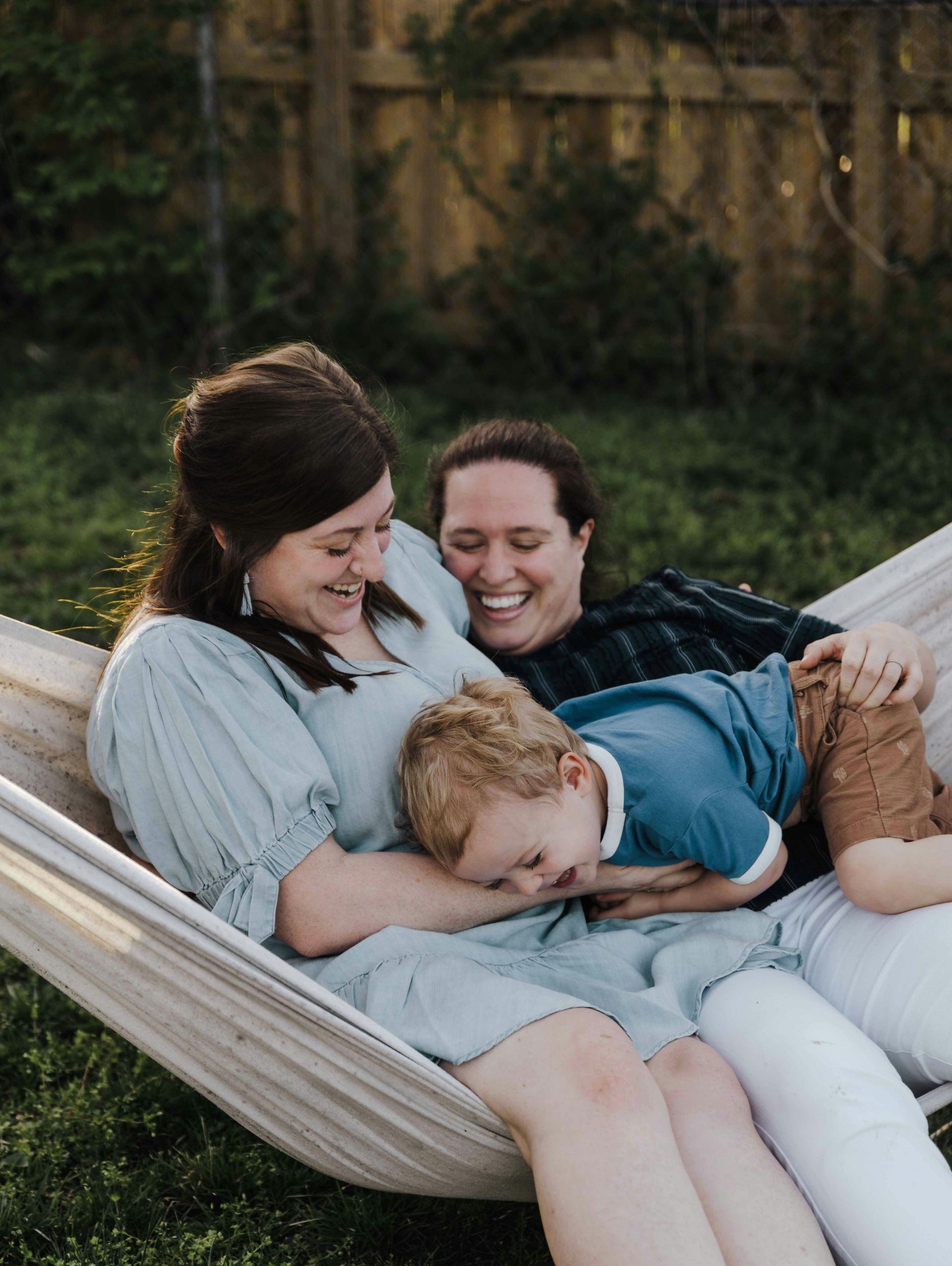 Two women and a child are sitting in a hammock.