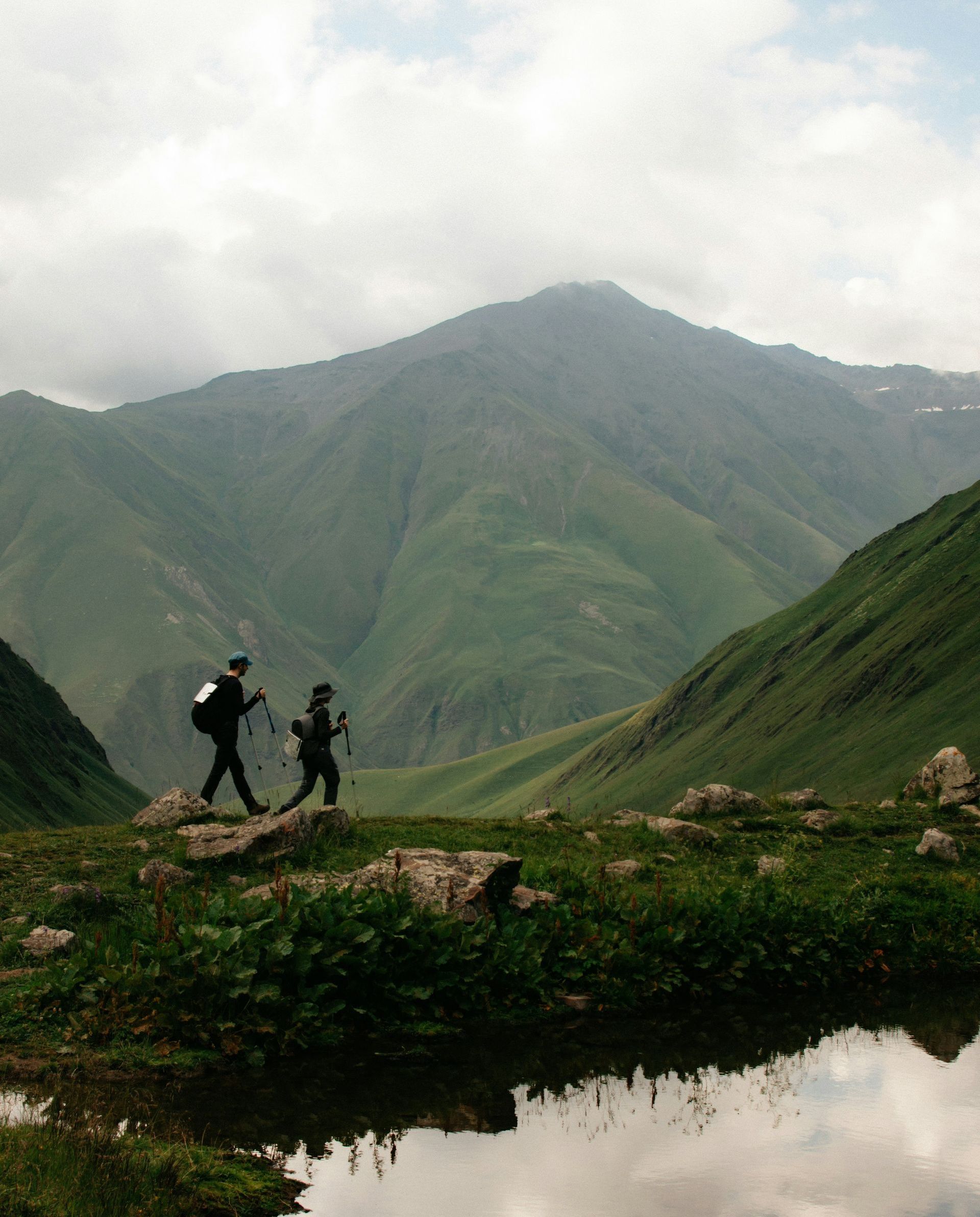 Two people hiking in the mountains with a lake in the foreground