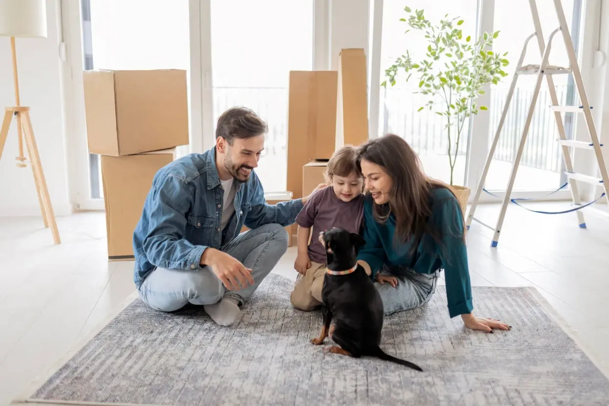 Family with a dog sitting on a rug in a bright living room during a moving day