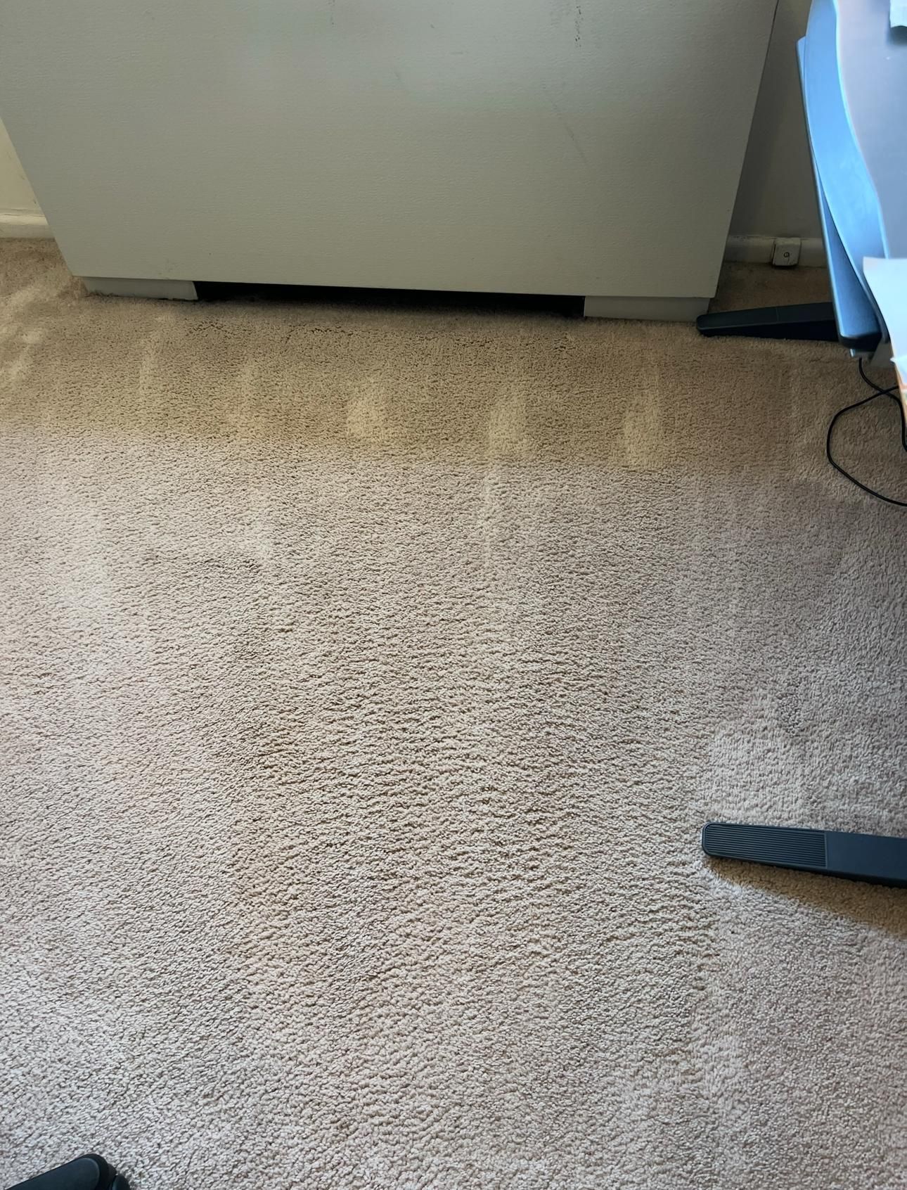 Carpeted floor beside a white cabinet, with part of a black chair leg and blue furniture visible.