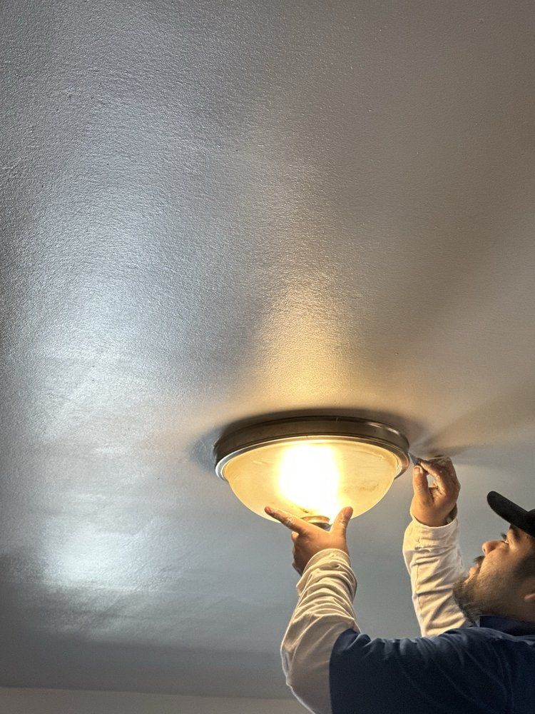 Person replacing a ceiling light fixture with a glowing glass shade