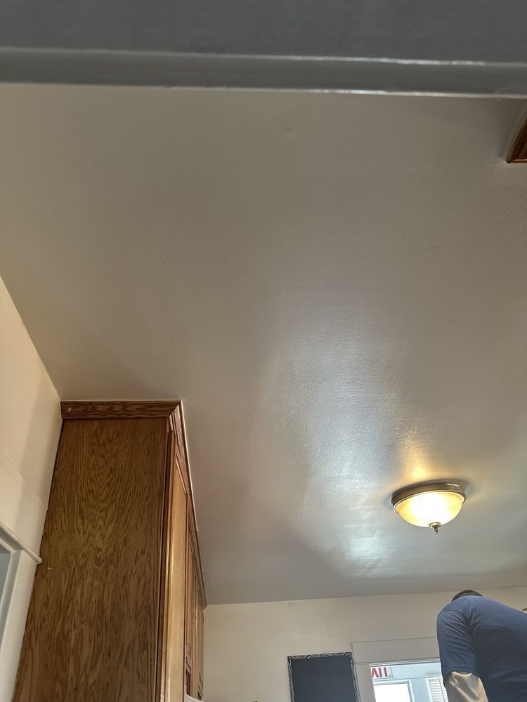 Indoor room ceiling with a lit flush-mount light and a person partially visible at the bottom right.