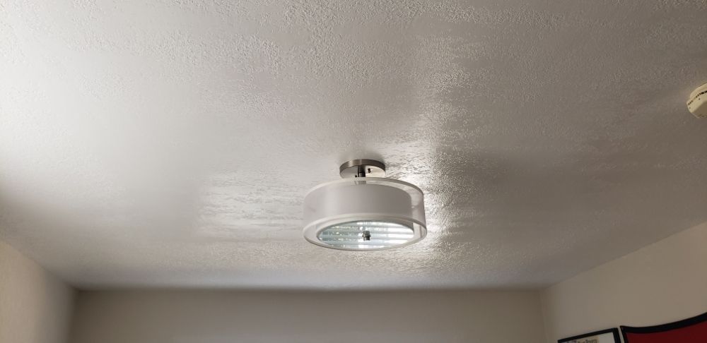 Ceiling-mounted white smoke detector centered on a textured white ceiling