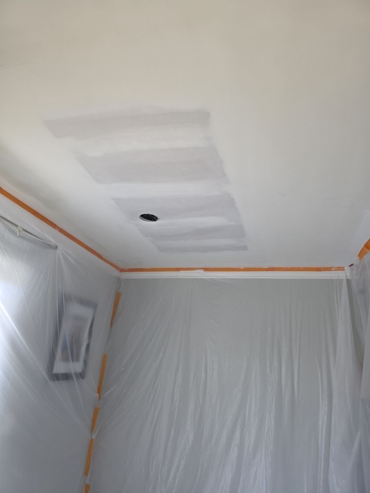 Plastic-covered room ceiling with taped edges, white walls, and a circular hole near the center.