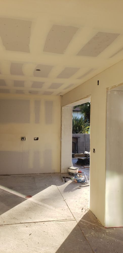 Unfinished room with drywall ceiling, open doorway, and tools on the floor during renovation