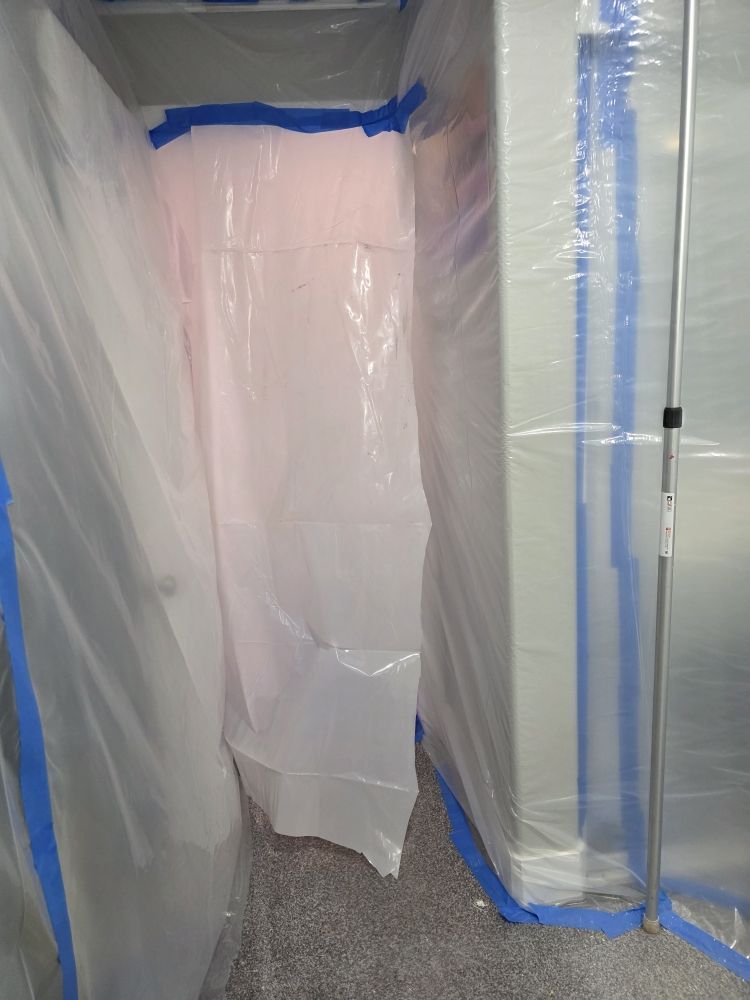 Plastic sheeting taped over a doorway in a partially covered interior space