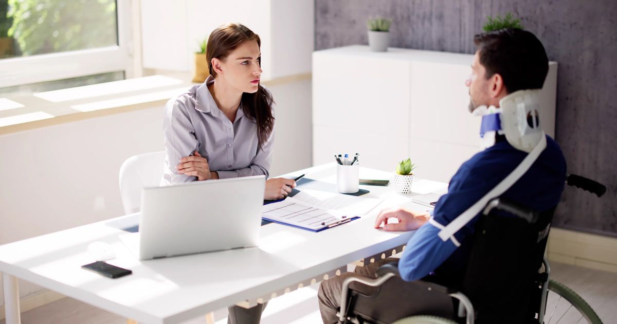 A man in a wheelchair is sitting at a desk talking to his lawyer Nyack NY Workers Compensation Law Firm - OGA Law.