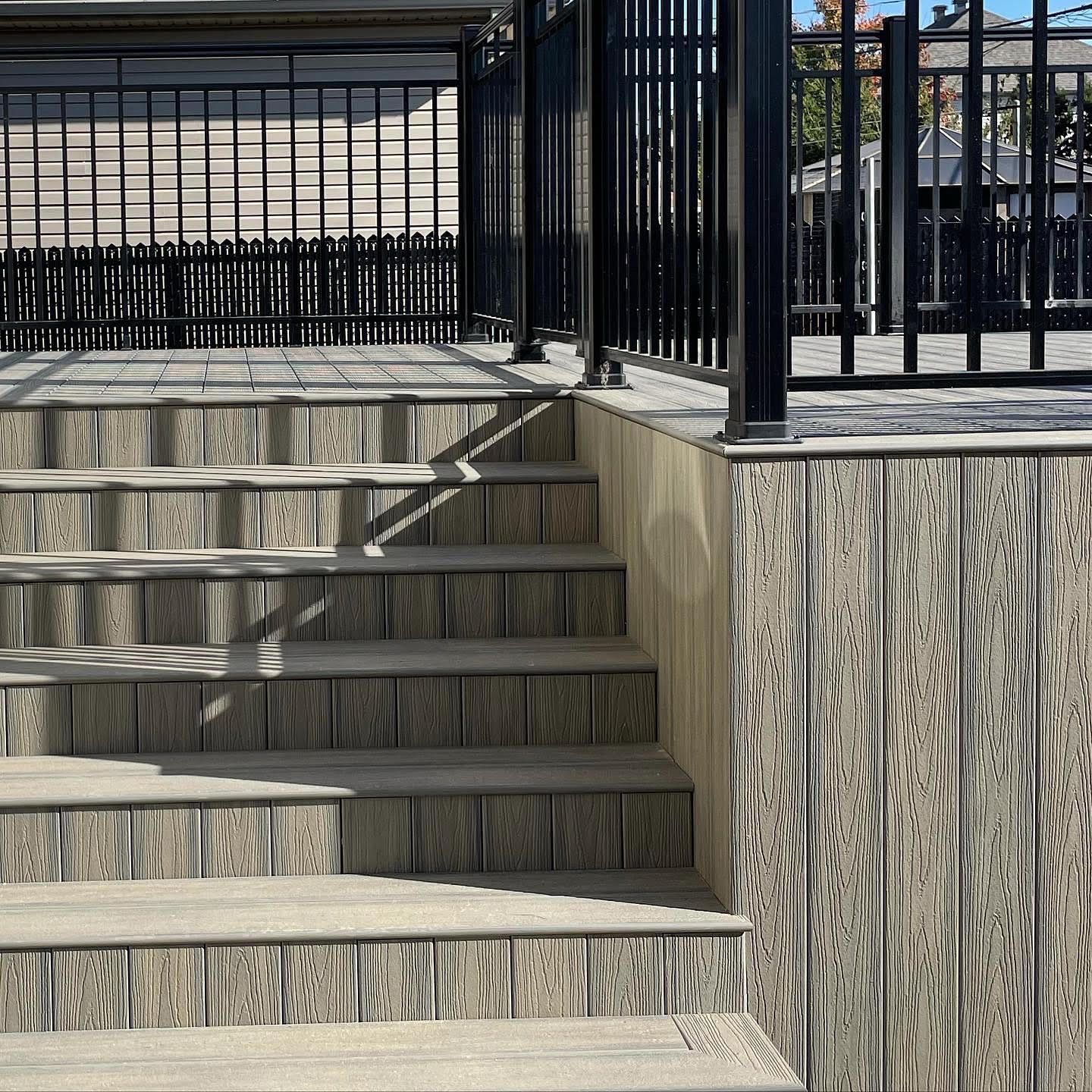 Escalier extérieur en bois avec rampe noire.
