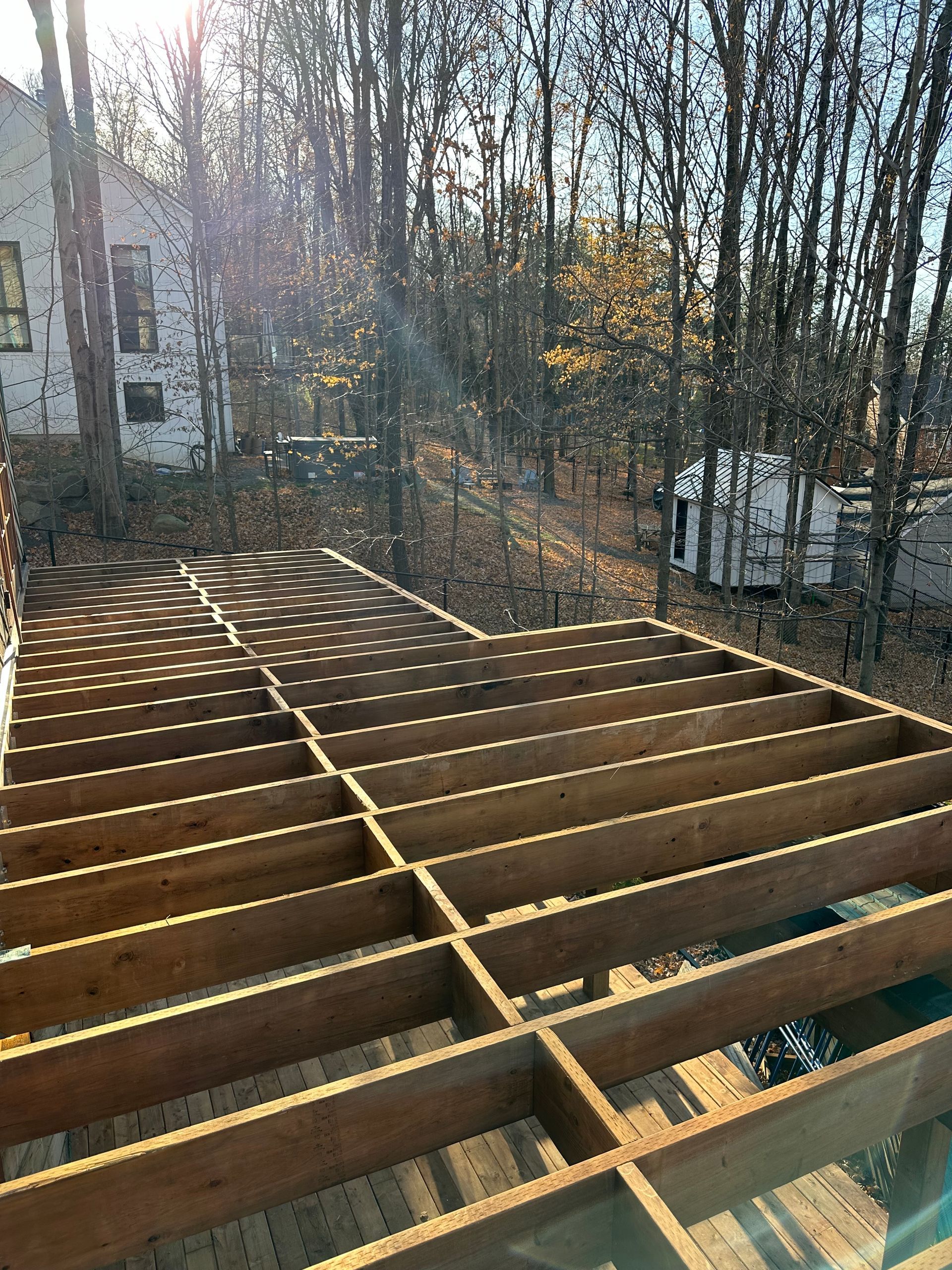 Construction d'une structure de terrasse en bois à l'extérieur, avec des arbres en arrière-plan.