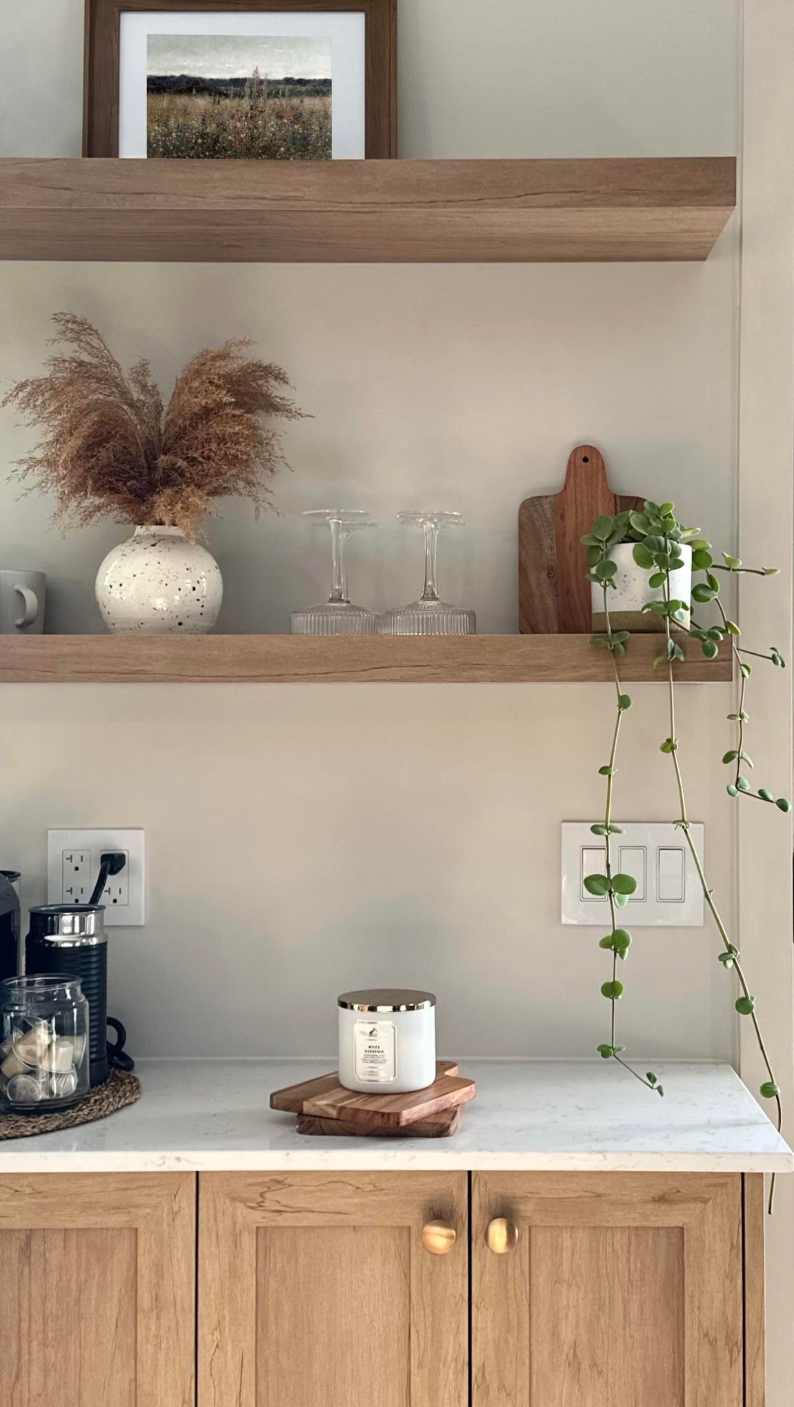 Étagères en bois avec décoration : vase d'herbes séchées, verrerie, planche à découper, plante retombante et nécessaire à café.