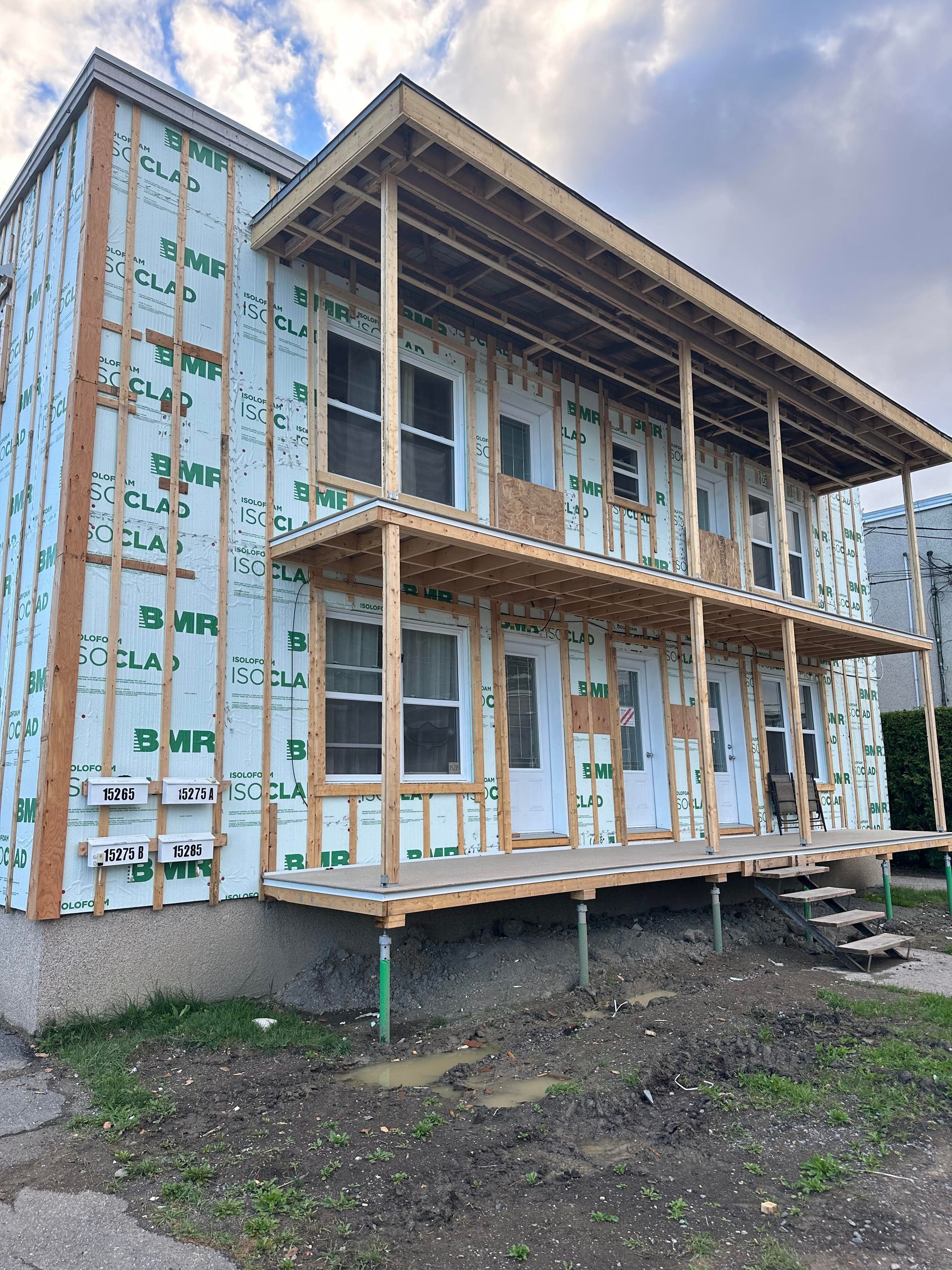 Immeuble en construction ; appartement de deux étages avec ossature bois, isolation verte et balcons non finis.