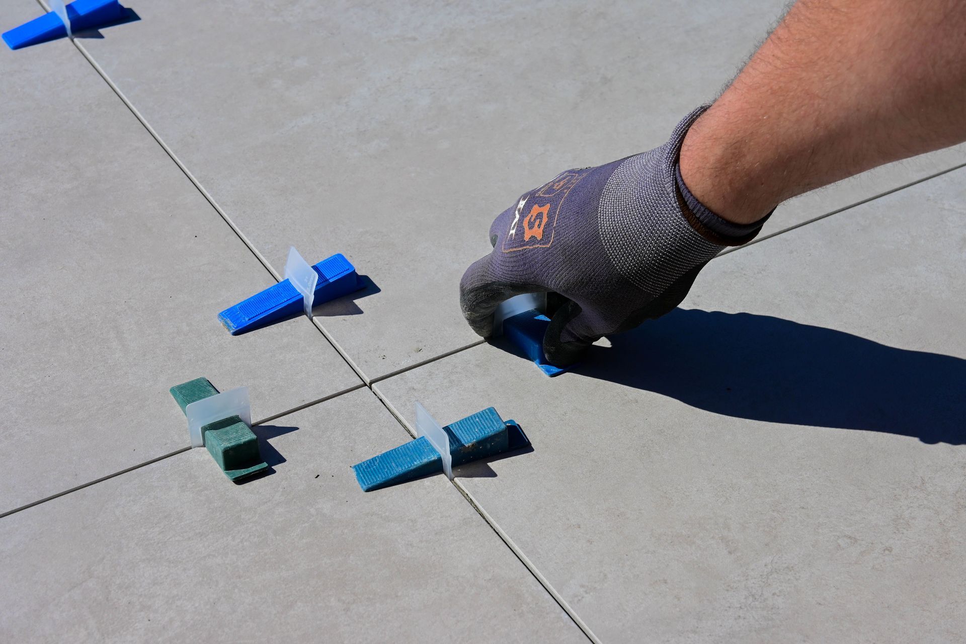 Main gantée ajustant un marqueur bleu à clip sur une surface en béton avec des lignes de traçage noires