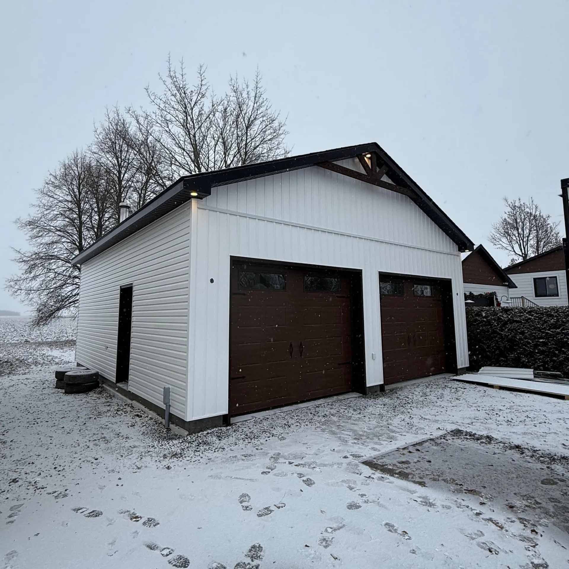 Garage blanc aux portes marron dans un décor enneigé.