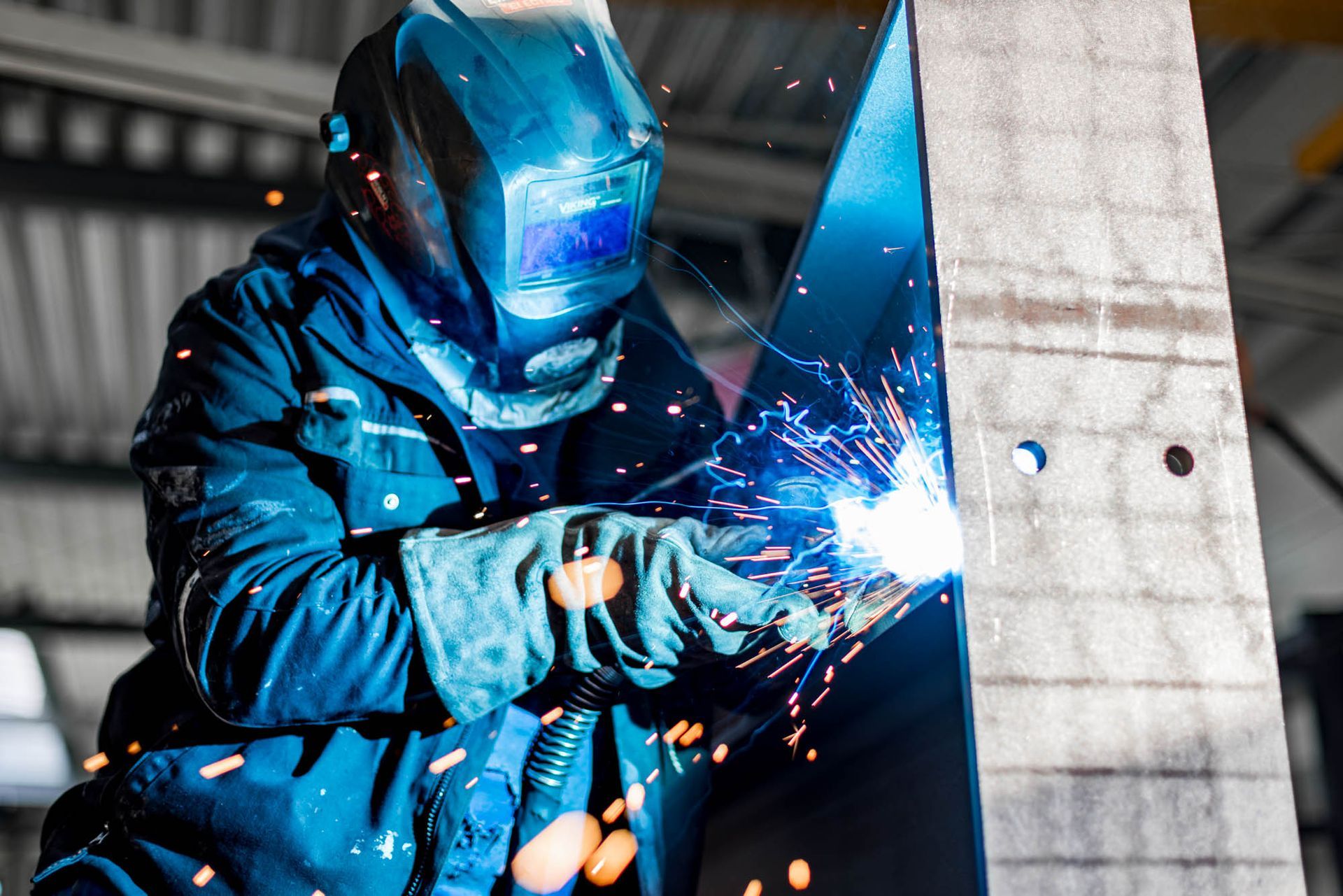 Ein Mann schweißt in einer Fabrik ein Stück Metall.