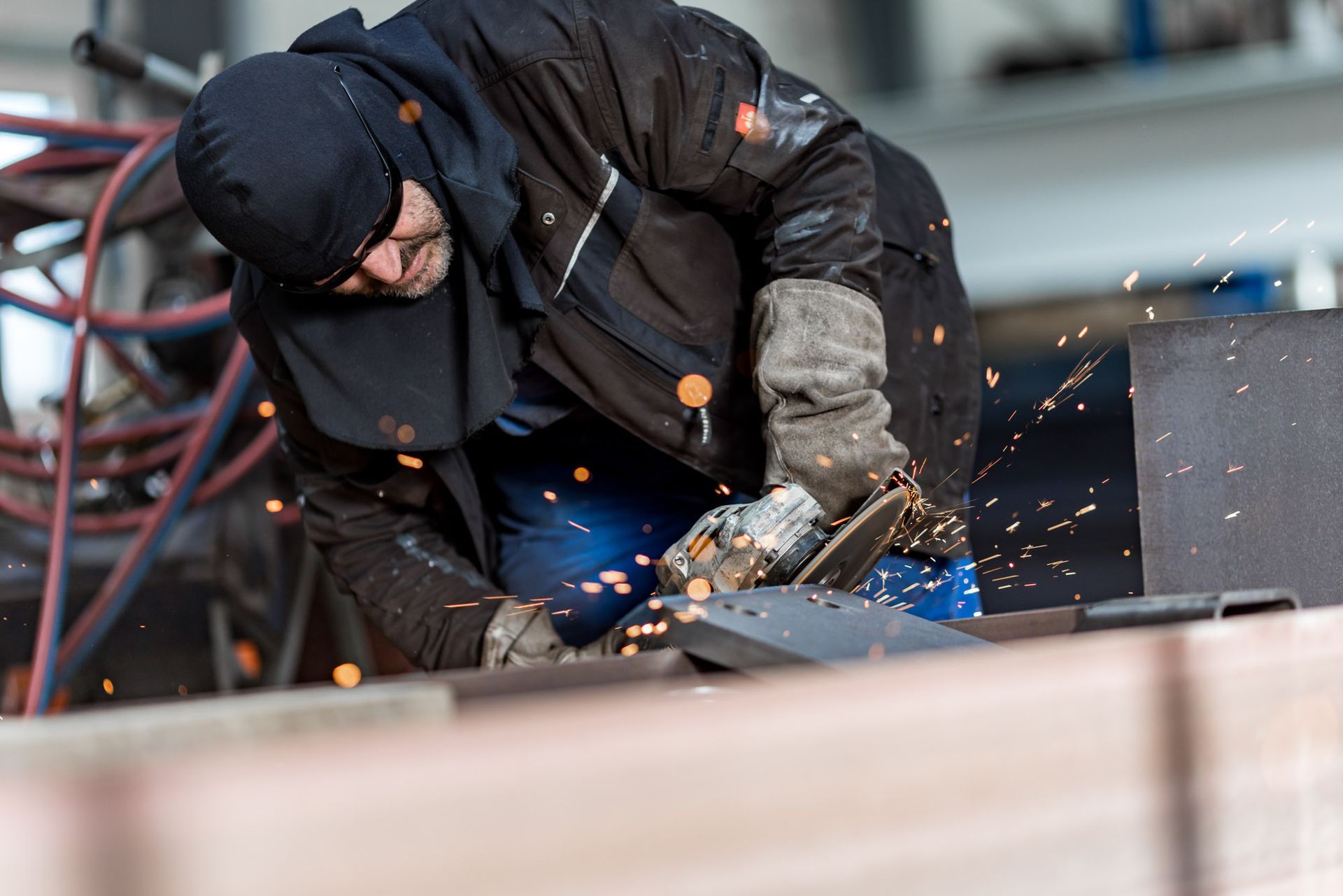 Ein Mann schleift in einer Fabrik ein Stück Metall.