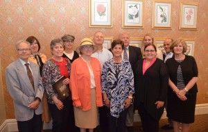 Group of people posing in front of a patterned wall with framed art.