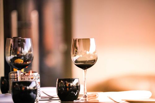 Two wine glasses on a softly lit table with candlelight and blurred warm background