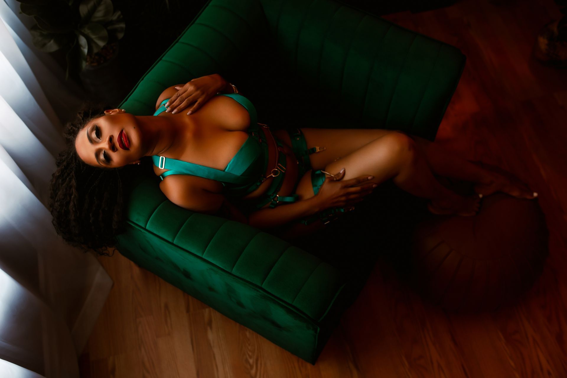 A woman in lingerie is laying on a green chair.