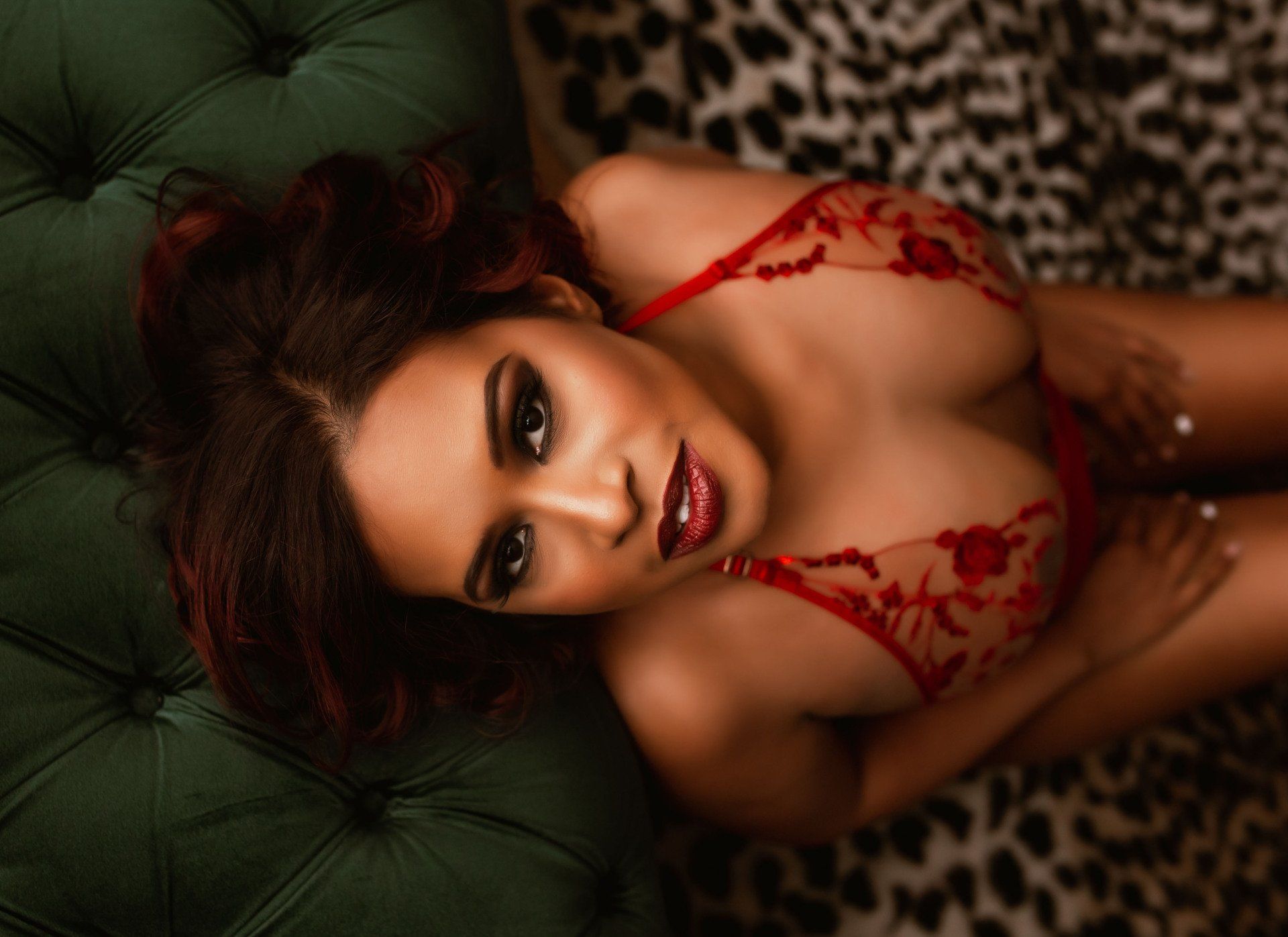 A woman in red lingerie is laying on a green couch.